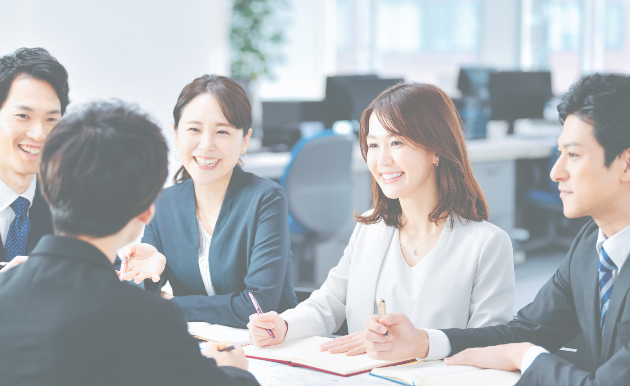 Two smiling businesswomen discussing work in an office.