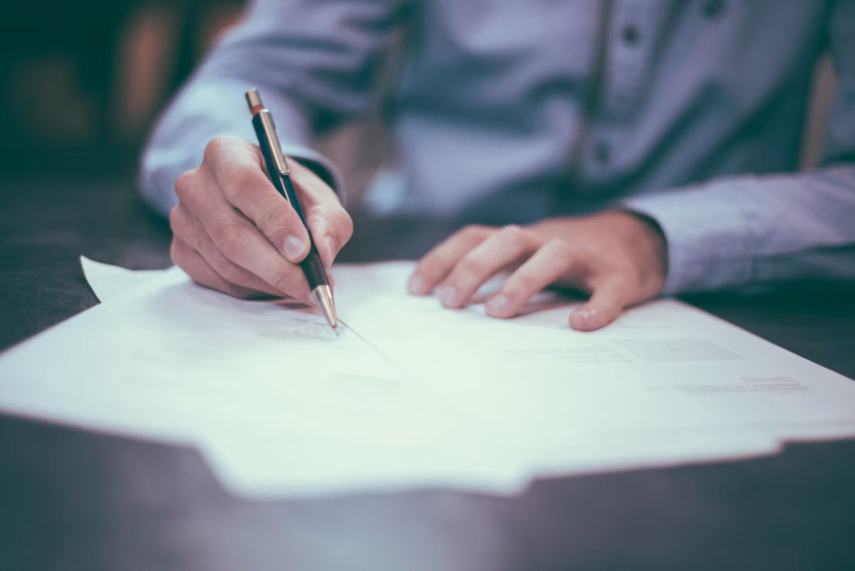 Close-up of hands signing a business document with a pen.